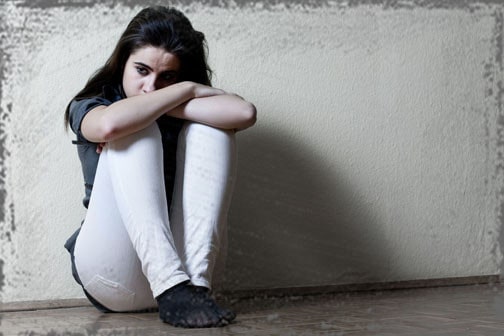 StandUpGirl girl curled in ball sits against wall