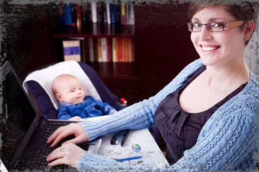 StandUpGirl mother on computer with baby next to her