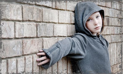 StandUpGirl girl with hood stands against wall